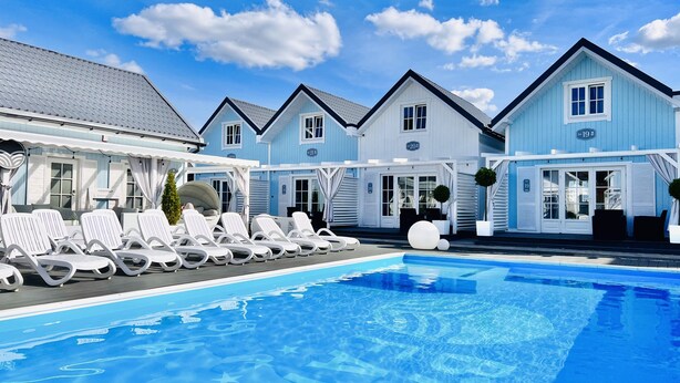 Área de piscina com espreguiçadeiras e piscina azul cristalina.