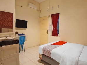 Habitació d'hotel amb llit, escriptori amb cadira, rentapins i mirall.