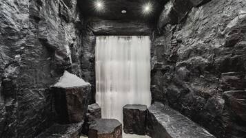 Walk through this serene corridor, featuring a stunning waterfall at the end, lined with benches and lit by overhead lights.