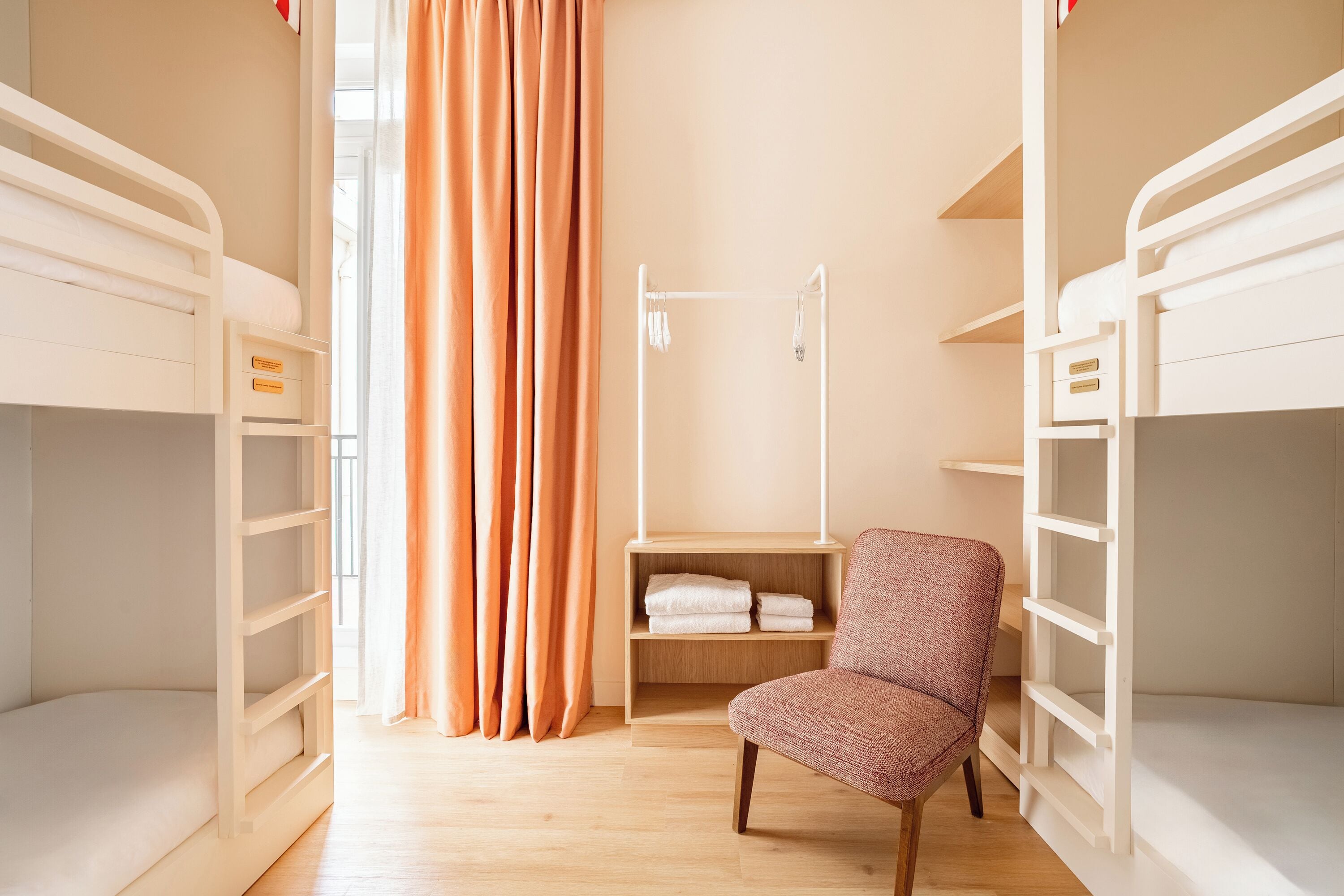 Un dormitorio con literas, una silla y una estantería.