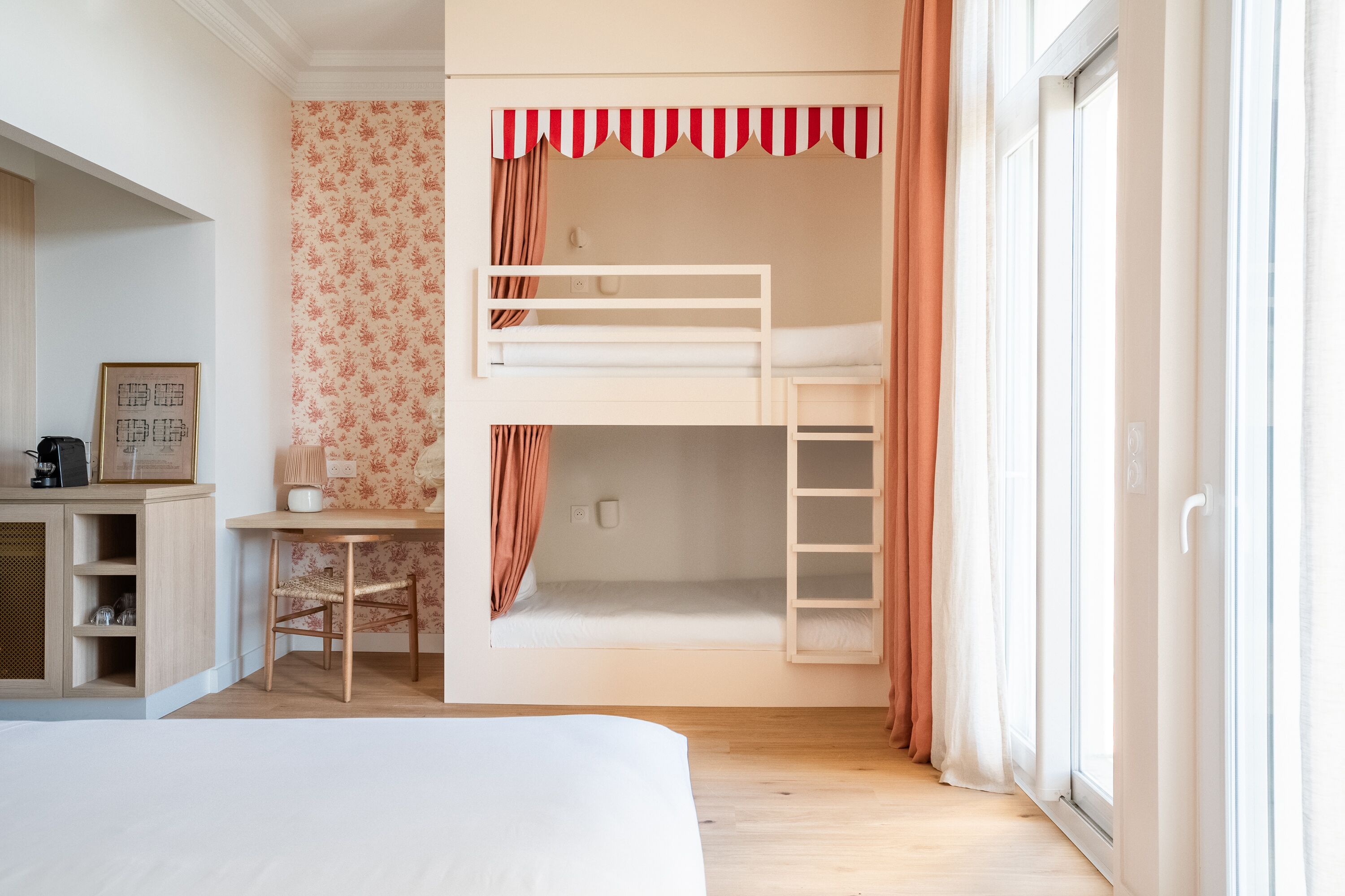 A bedroom with bunk beds, a desk, and a cabinet.