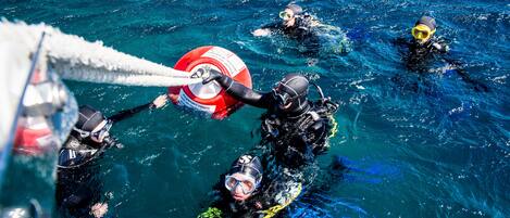 Un grupo de buzos en aguas cristalinas, equipados con equipo de scuba y un flotador salvavidas.