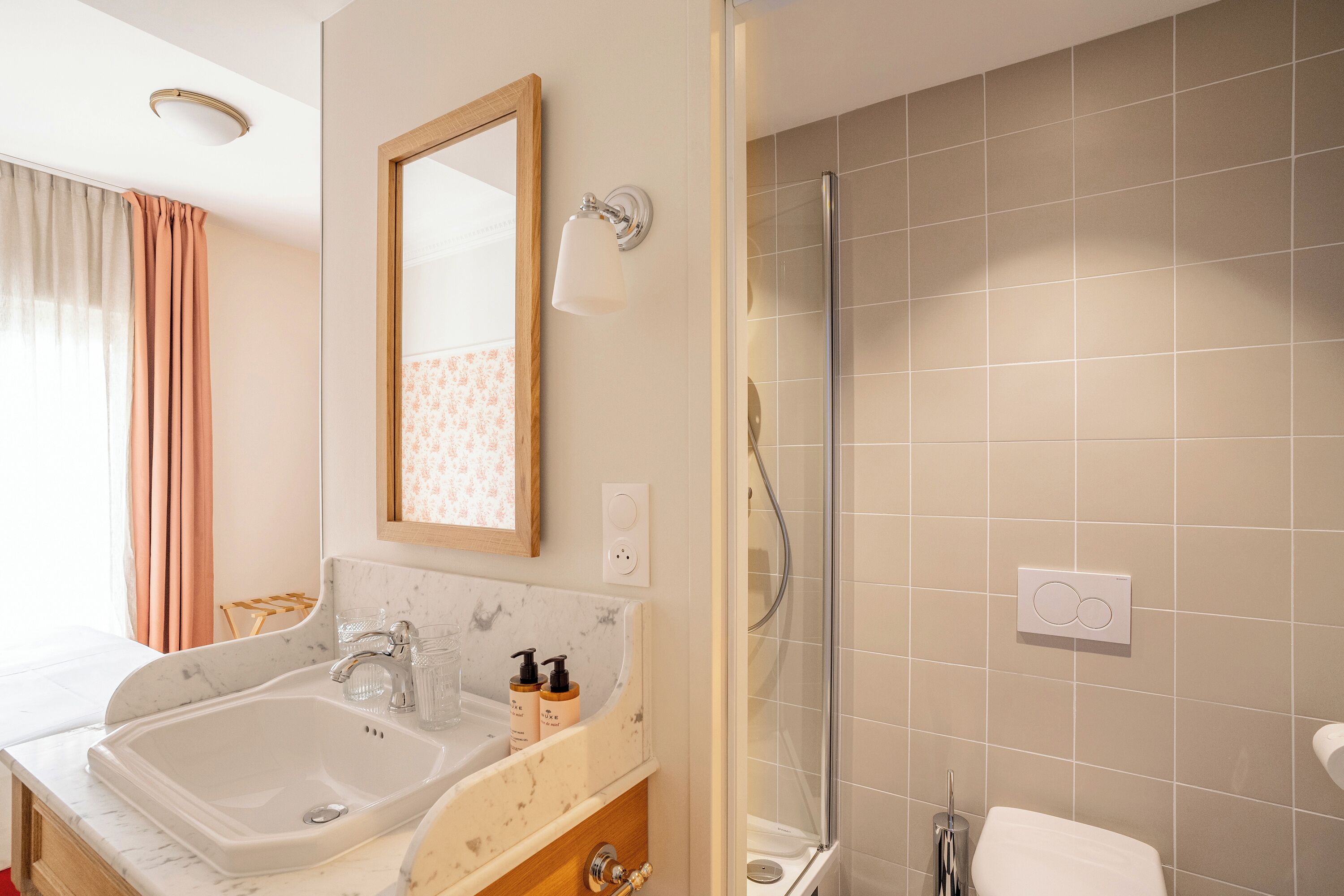 A bathroom with a double sink, a mirror, a shower, and a toilet.