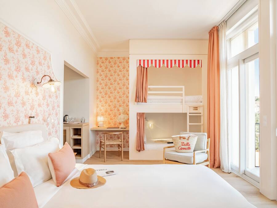 A bedroom with a bunk bed, a desk, a chair, and a bed with pillows.