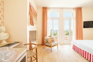 Une pièce comprenant un lit, une chaise, un bureau avec un ordinateur portable, une fenêtre avec des rideaux et une vue sur l’extérieur.
