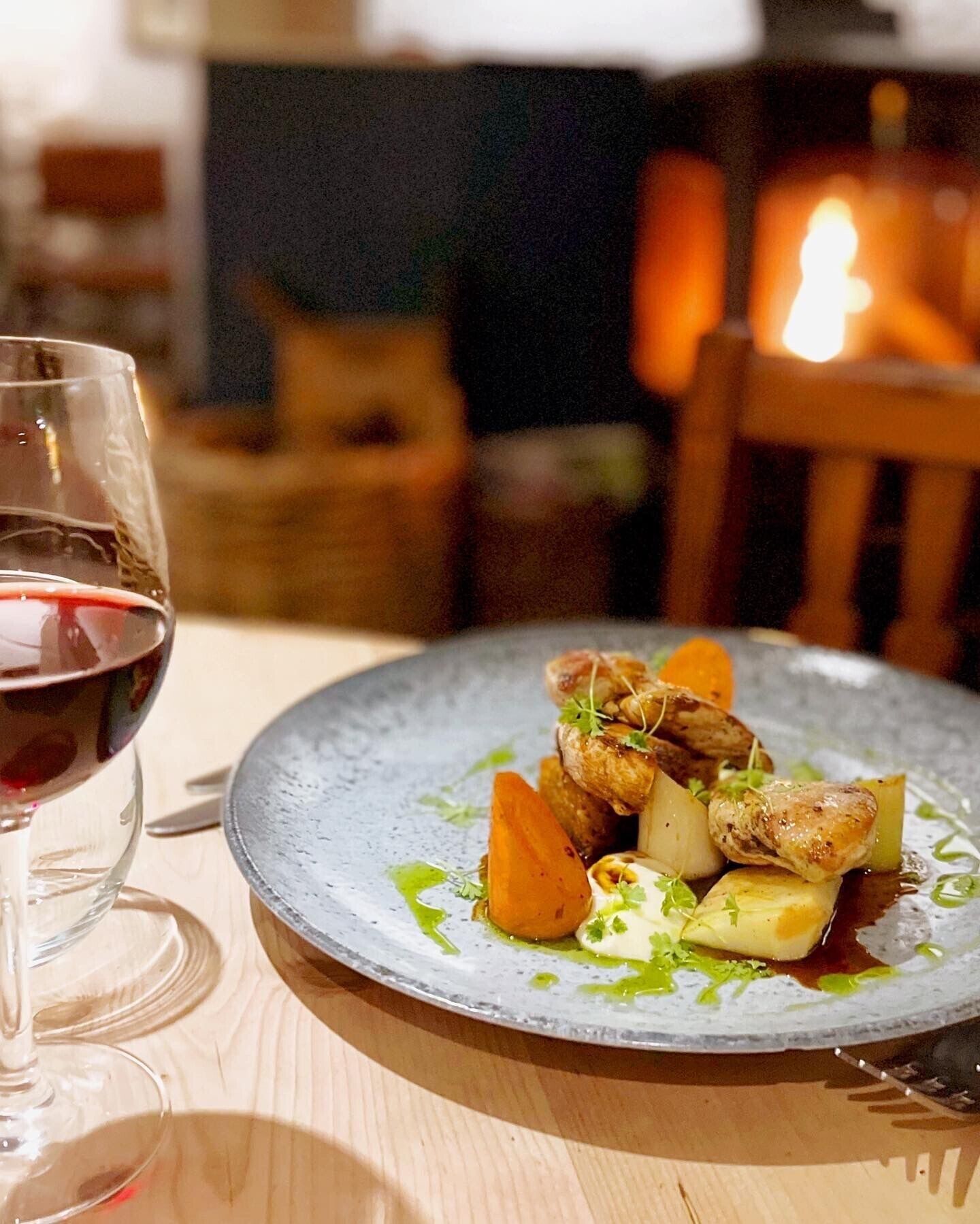 Una mesa de comedor con un plato de comida y una copa de vino tinto.