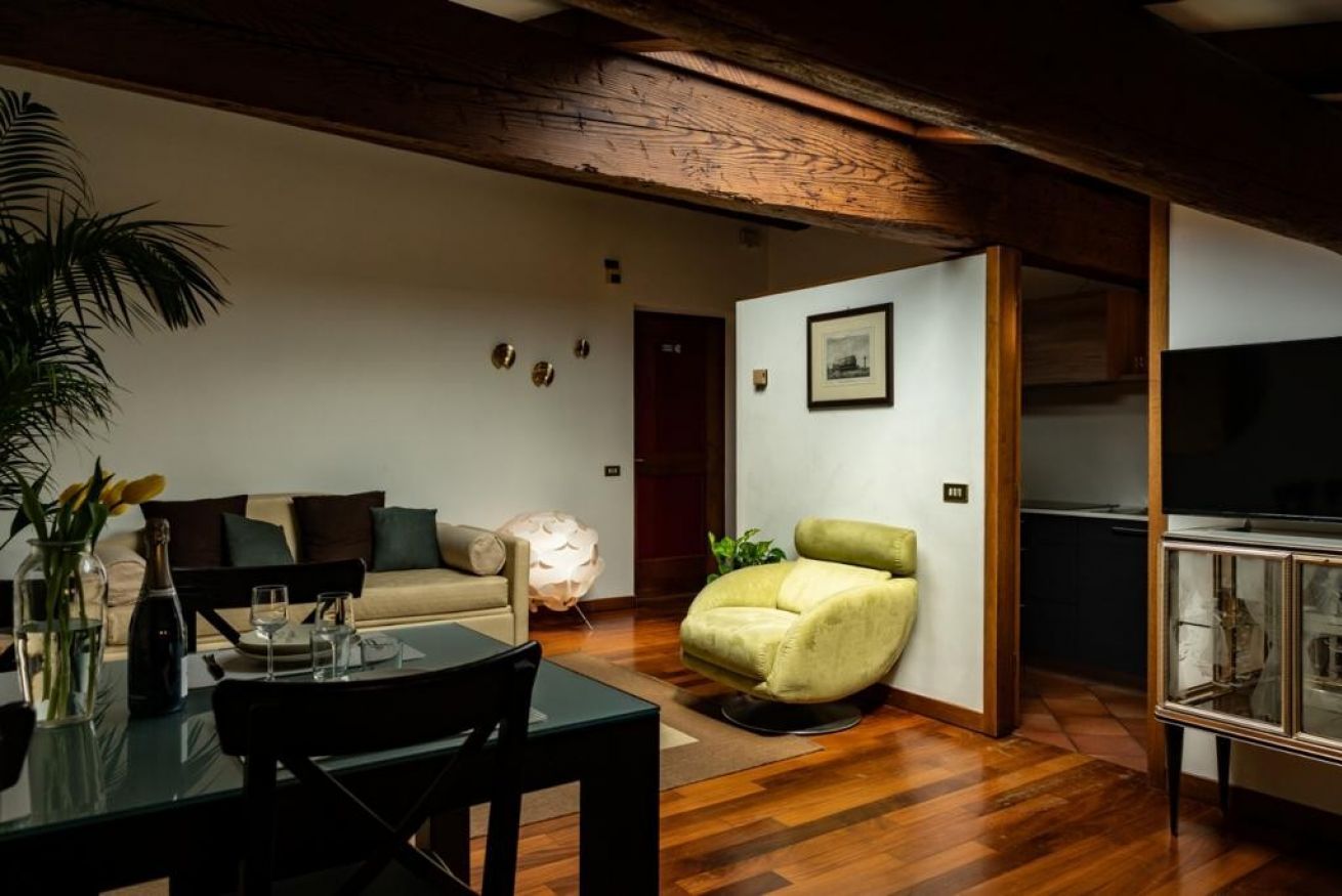 Un soggiorno moderno con un divano, una poltrona verde, un tavolo da pranzo con sedie e una televisione su un mobile.