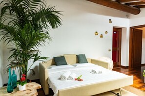 A hotel room with a bed, a large potted plant, and a wooden side table with two vases. - Luxurious Arena Residence, 80 meters from the Arena (Verona)