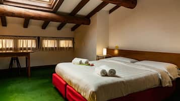 Una camera d'albergo con soffitto in legno, un letto con lenzuola bianche, una scrivania e un tappeto verde.
