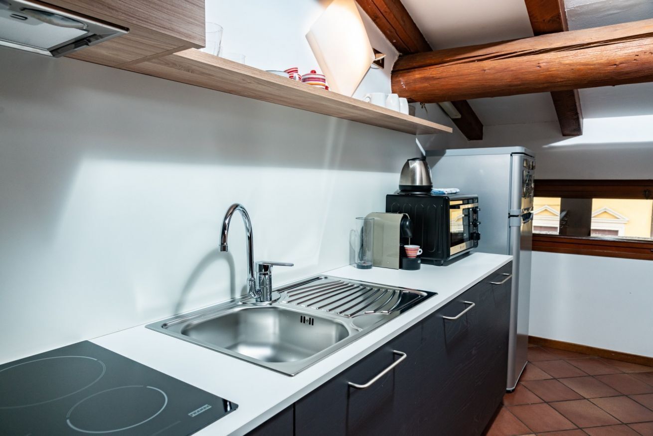 Een koffiezetapparaat/waterkoker, een koelkast, een oven, een kookplaat