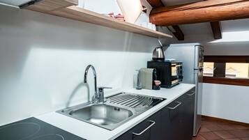 Een koffiezetapparaat/waterkoker, een koelkast, een oven, een kookplaat