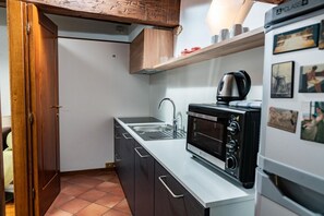 Een kleine keuken met een ingebouwde magnetron, een spoelbak en een koelkast.