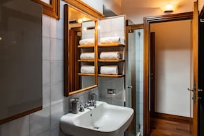 A modern bathroom with a white sink, a mirror with wooden frames, and a towel rack with multiple towels. - Luxurious Residence Arena, 80 meters from the Arena (Verona)