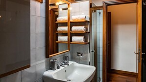 Casa de banho moderna com lavatório branco, espelho com moldura de madeira e toalheiro com várias toalhas.