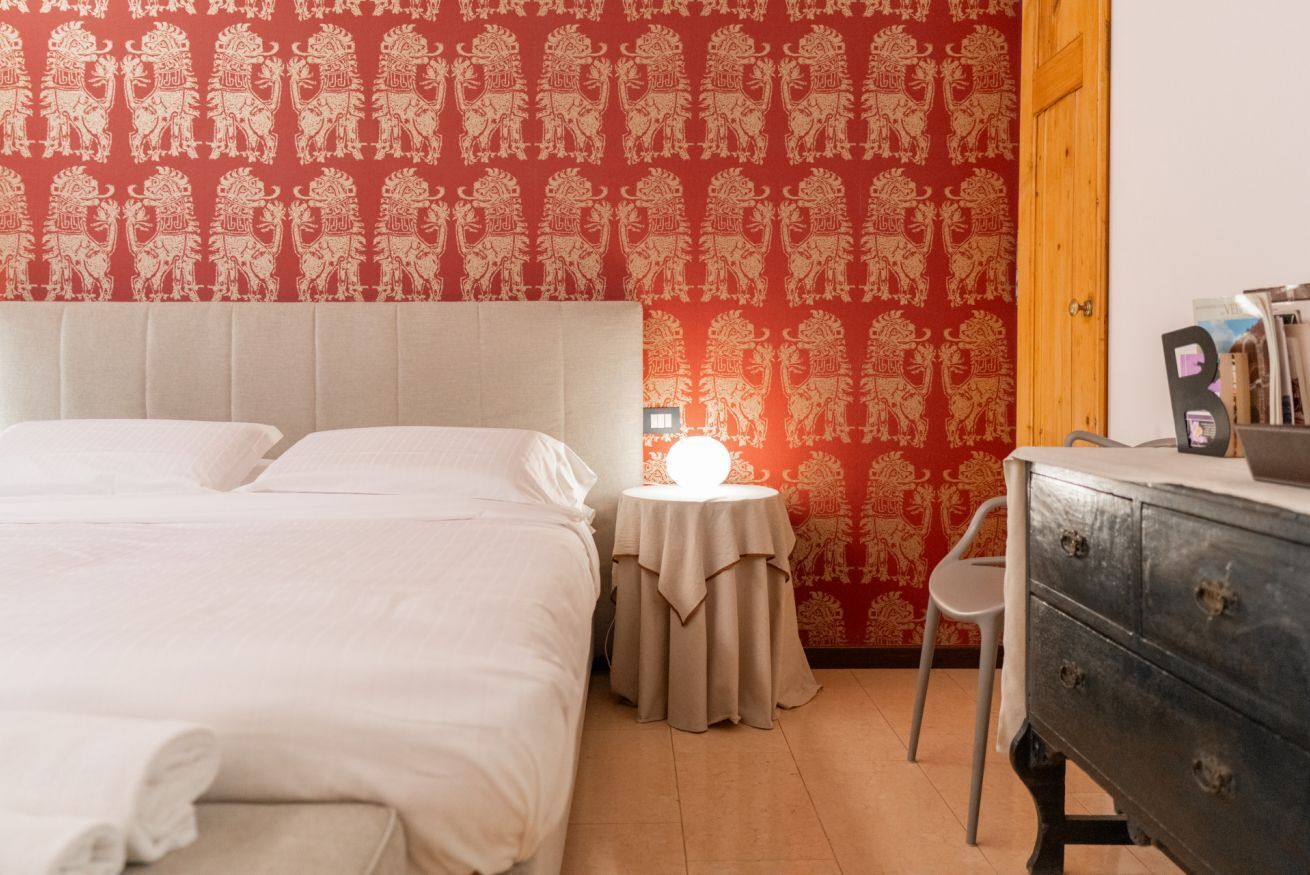 Ein Schlafzimmer mit einem Bett, einem Nachttisch mit Lampe, einem Sessel und einer Kommode.