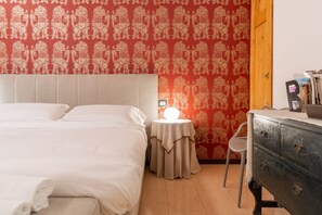 A bedroom with a bed, a bedside table with a lamp, a chair, and a dresser.