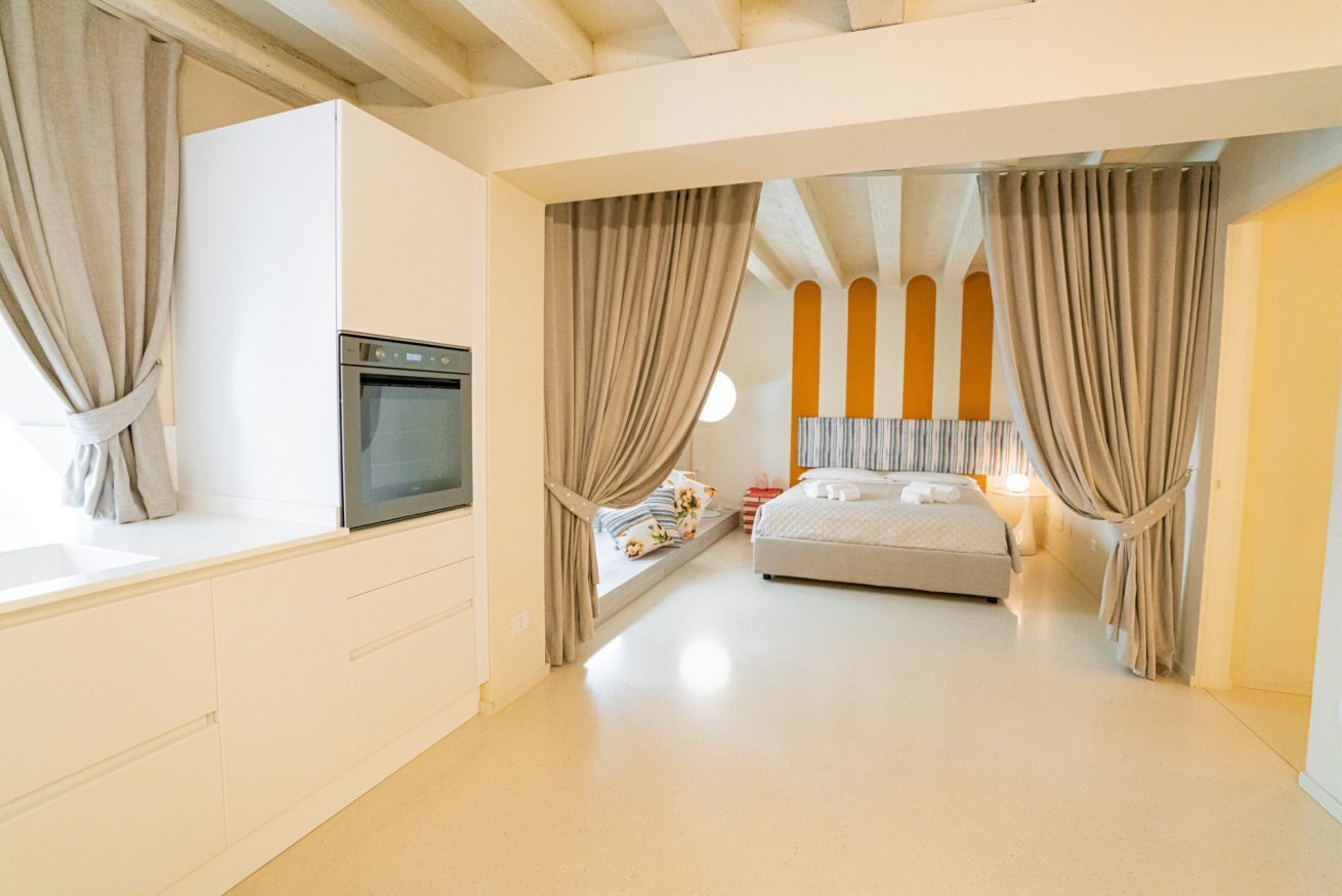 Une chambre moderne avec un lit, un four encastré et une fenêtre avec des rideaux.