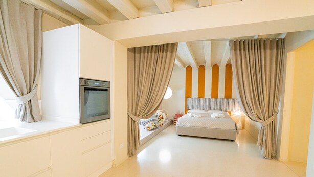 Un dormitorio moderno con una cama, horno empotrado y ventana con cortinas.