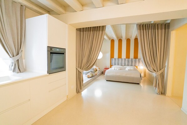 Une chambre moderne avec un lit, un four encastré et une fenêtre avec des rideaux.