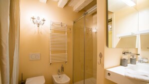 Une salle de bain comprenant des toilettes, un bidet, une douche à parois de verre et un lavabo avec un miroir.