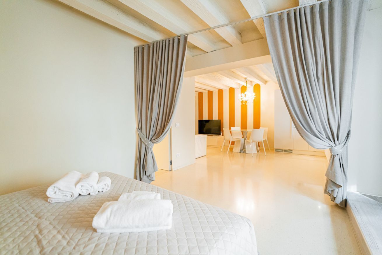 Ein Hotelzimmer mit Bett, Vorhängen, Fernseher, Schreibtisch und Stuhl.