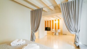 Une chambre d’hôtel avec un lit, des rideaux, une télévision, un bureau et une chaise.