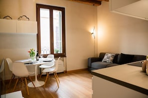 Un espace de vie compact comprenant un coin repas, un canapé et une fenêtre donnant sur un paysage agréable.