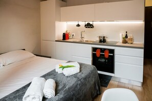 Een moderne hotelkamer met een bed, een kleine kitchenette en een badkamer.