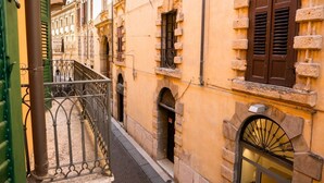 Una calle estrecha flanqueada por edificios con fachadas de piedra y contraventanas de madera.
