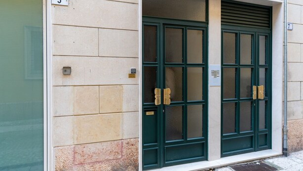 A building entrance with a beige facade, numbered 5, featuring a green double door with a small sign above it. - Large Filippini Residence a few meters from the Arena (Verona)