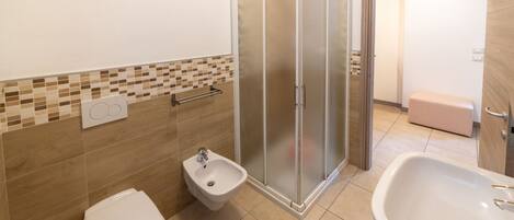 Un baño con ducha, bidé, inodoro y lavamanos.