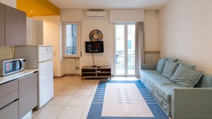 A compact living space with a kitchenette, a flat-screen TV, a sofa, and a patterned rug. - Large Filippini Residence a few meters from the Arena (Verona)