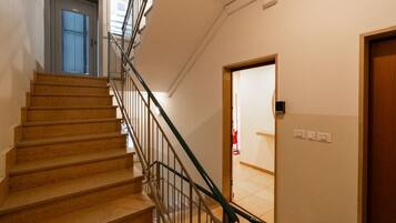 Un escalier avec une rampe en métal, une porte en haut et un interrupteur sur le mur.