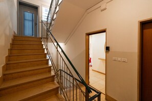 A staircase with a metal railing, a door at the top, and a light switch on the wall. - Large Filippini Residence a few meters from the Arena (Verona)
