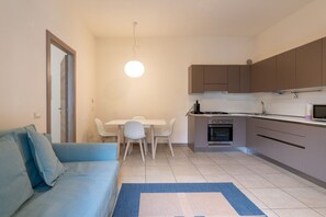 Un espace de vie compact comprenant un coin cuisine, un coin repas et un canapé.