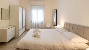 A bedroom with a bed, a dresser, a mirror, a chair, and a window with curtains. - Large Filippini Residence a few meters from the Arena (Verona)