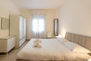 A bedroom with a bed, a dresser, a mirror, a chair, and a window with curtains. - Large Filippini Residence a few meters from the Arena (Verona)