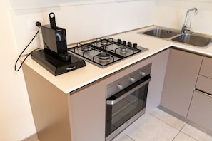 Una cocina con estufa a gas, horno y cafetera sobre la encimera.