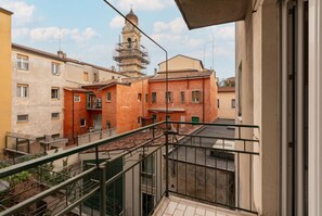 A residential area with a tower and buildings, a balcony with a metal railing, and a clear sky.