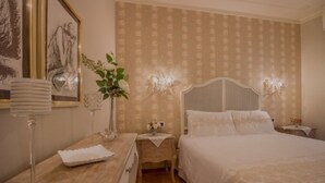 Een slaapkamer met een bed, een nachtkastje, een dressoir en een wandlamp.