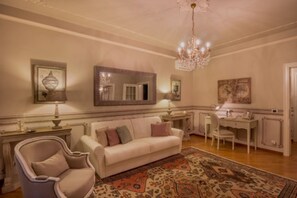 A well-lit living room with a chandelier, a sofa, a chair, a desk, and a mirror. - Enchanting Residence in front of Giulietta's House (Verona)