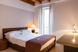A neatly made bed with white linens, a wooden headboard, and a bedside table with a lamp. - Magnificent Residence overlooking Piazza Erbe (Verona)