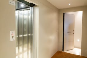 A modern elevator with a control panel, a door, and a hallway leading to another room. - Magnificent Residence overlooking Piazza Erbe (Verona)