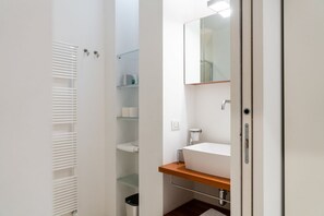 A modern bathroom with a white sink, mirror, and built-in shelves. - A magnificent residence overlooking Piazza Erbe (Verona)