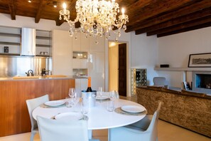 A modern dining area with a round table set for four, a bar area with a wooden counter, and a chandelier. - Magnificent Residence overlooking Piazza Erbe (Verona)