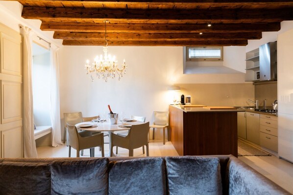 Una cocina moderna con techo de madera, una zona de comedor con candelabro y un sofá en primer plano.