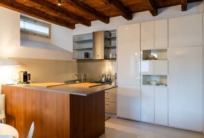 A modern kitchen with a wooden island, white cabinetry, and a built-in stove. - Magnificent Residence overlooking Piazza Erbe (Verona)