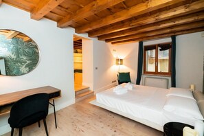 A bedroom with a bed, a desk, a chair, a lamp, and a window with curtains.