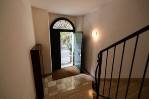 Un escalier mène à un espace extérieur doté d’une porte et d’un petit jardin que l’on peut apercevoir à travers l’ouverture.