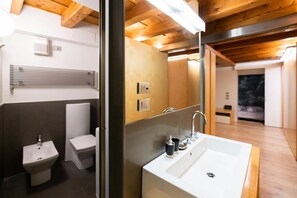 Een moderne badkamer met een groot wastafel, toilet, bidet en een spiegel.